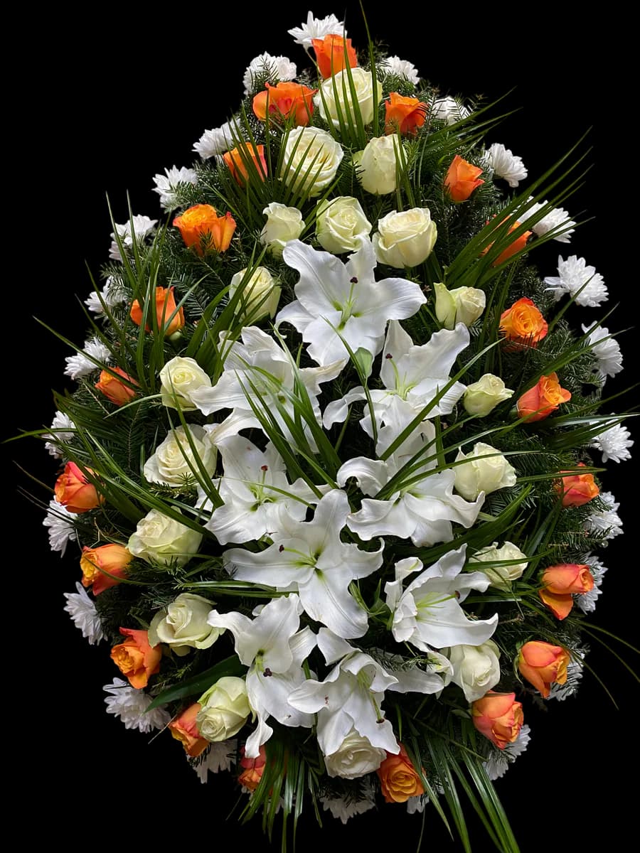 Coroană funerară cu trandafiri portocalii, crini albi și verdeață tropicală pe stativ