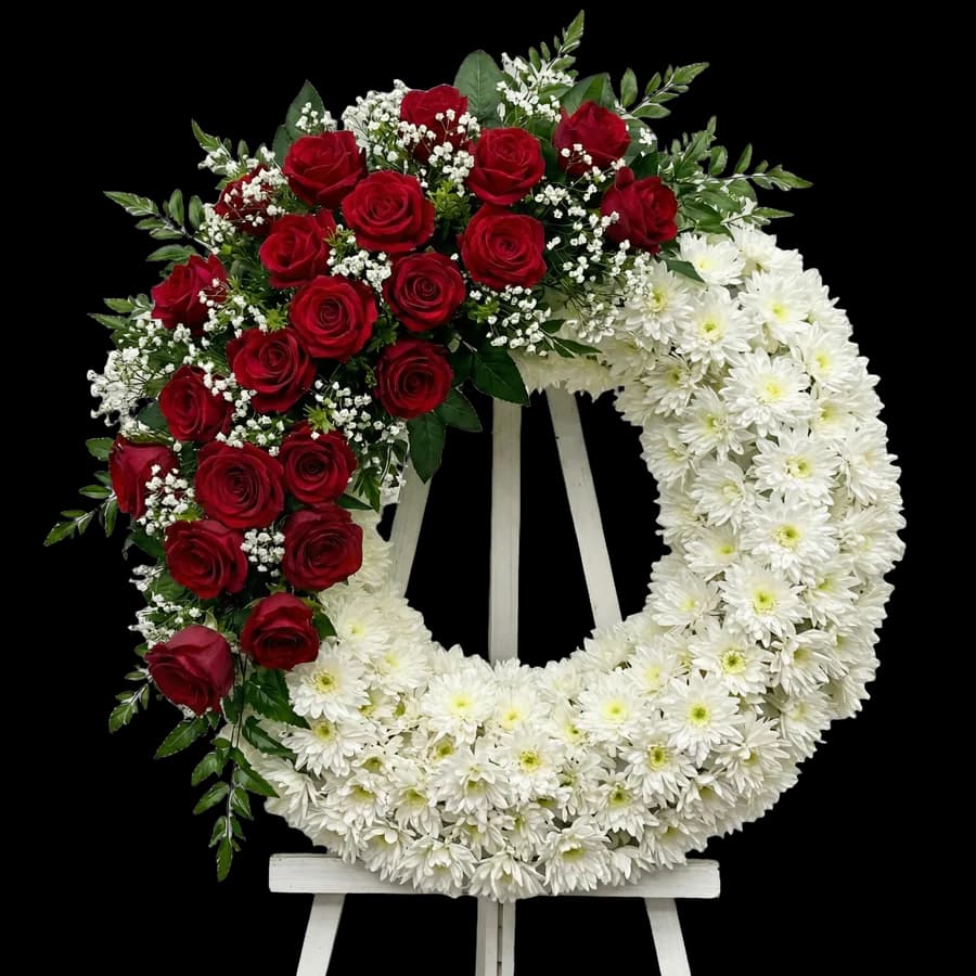 Coroană funerară rotundă cu trandafiri roșii și crizanteme albe pe stativ